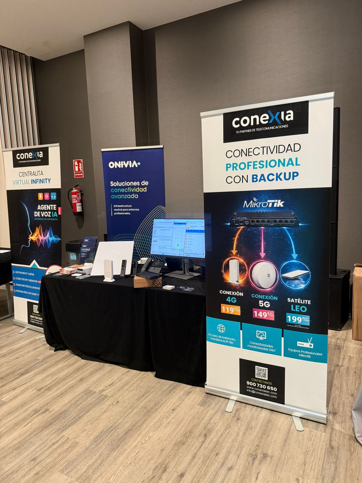Stand de Conexia con roll-ups de Centralita Virtual Infinity, Onivia y Conectividad Profesional con Backup